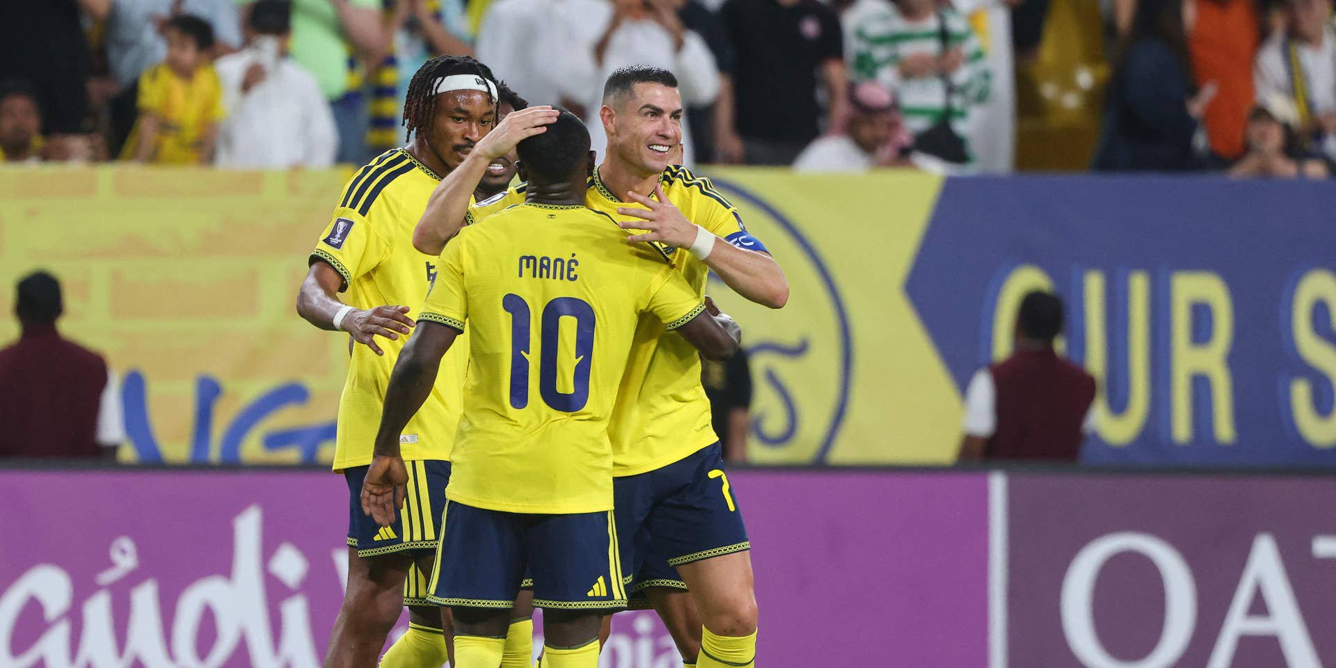 Cristiano Ronaldo gratuliert Sadio Mané und weiteren Mitspielern im gelben Al-Nassr-Trikot auf dem Spielfeld.