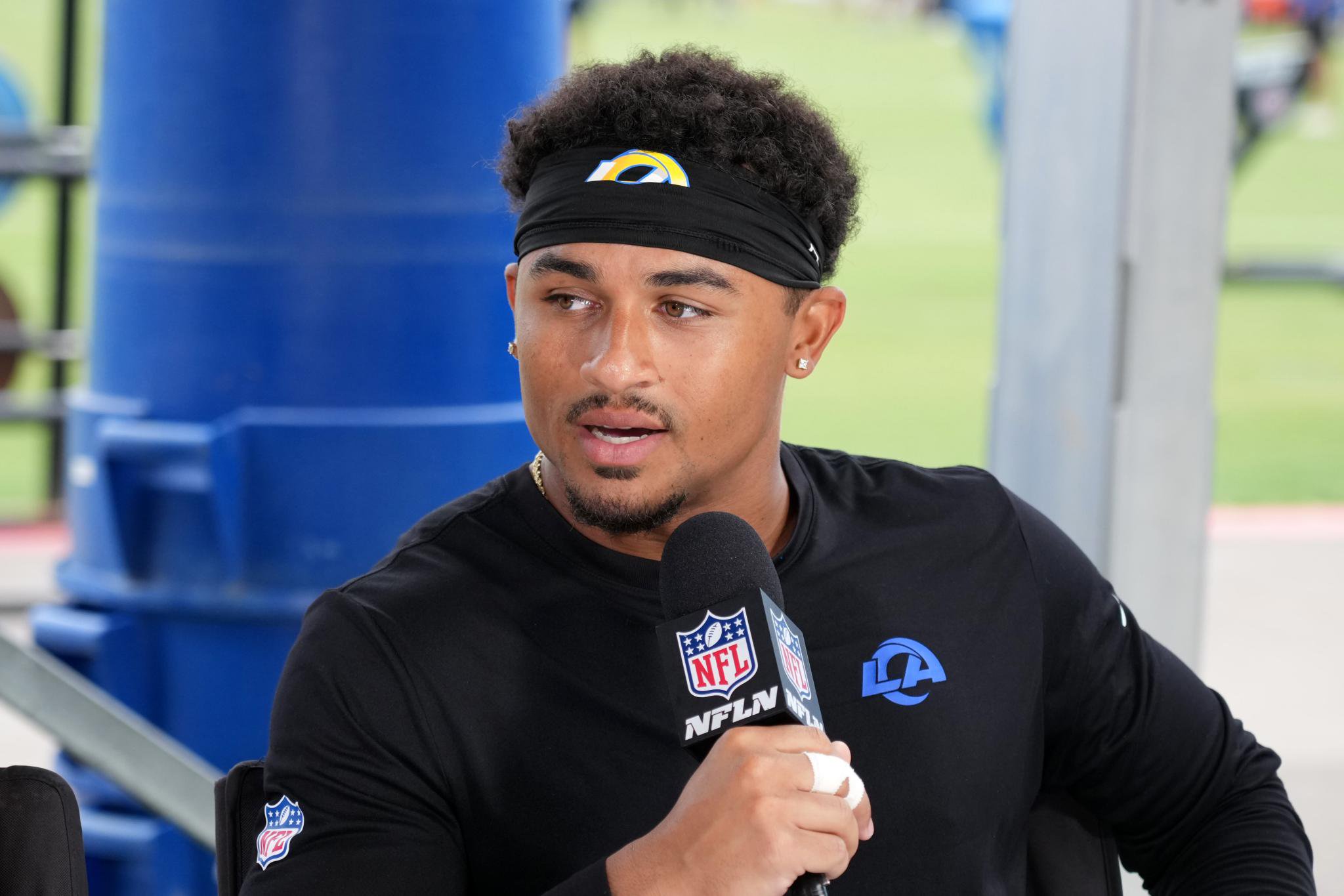 A football player wearing a black headband with a yellow and blue team logo, a black long-sleeved shirt with "LA Rams" logo, speaks into an NFL Network microphone.