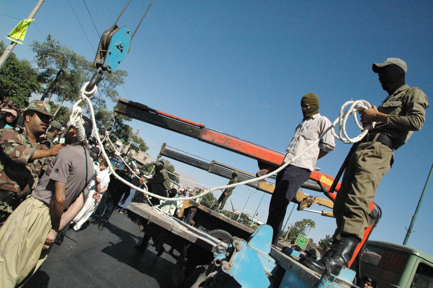 Masked Iranian soldiers and government employees preparing to publicly hang a condemned man in Shiraz.