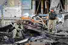 Soldiers work in the area as the building and the surrounding vehicles are reduced to wreckage after a Russian air strike on a post office in Ukraine's Kharkiv region