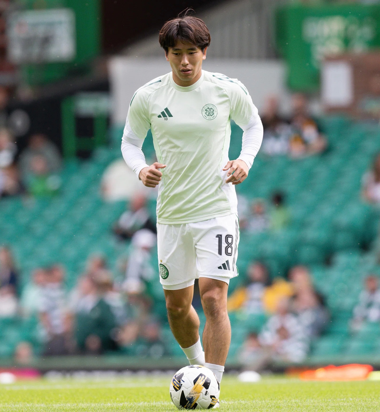 Yamada in Celtic training kit controls the ball on the pitch during a match warm-up.