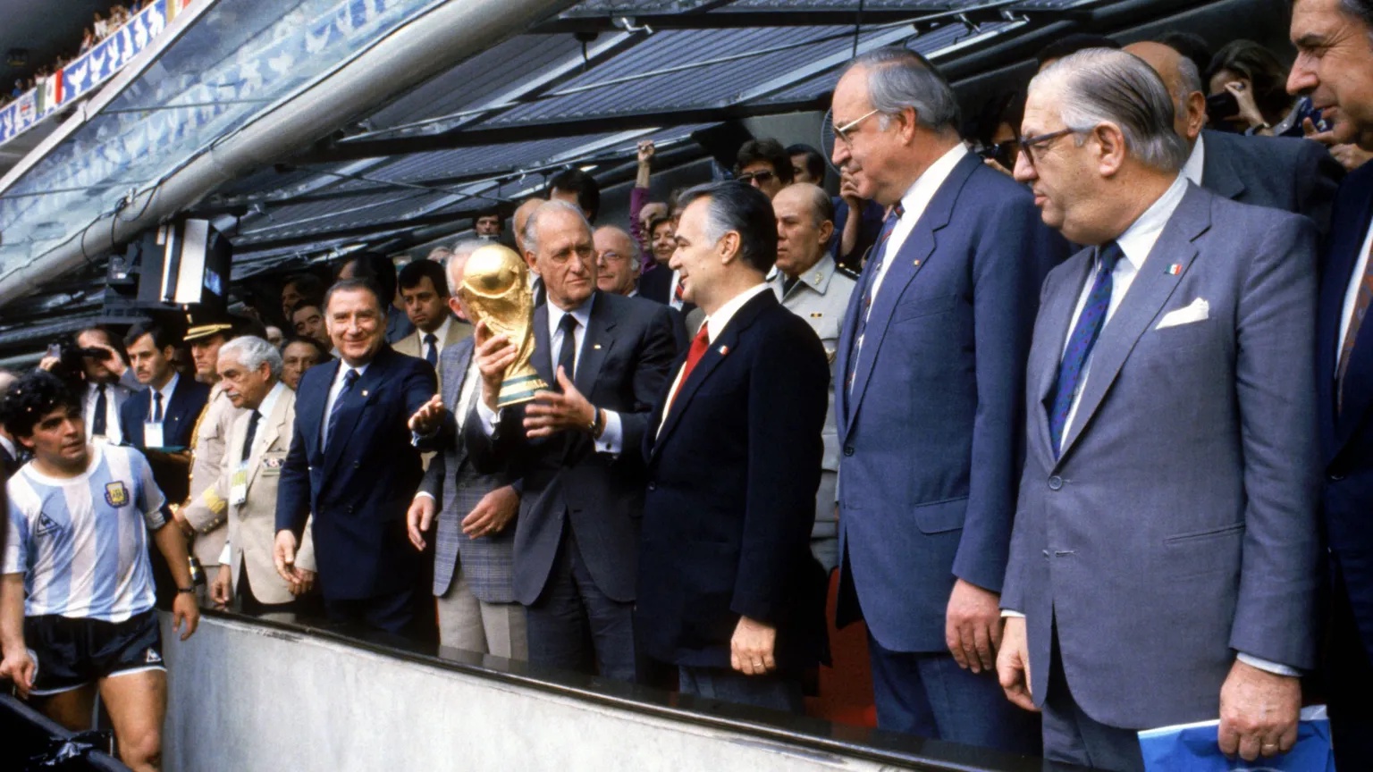 Peter Robinson/Alamy A Peter Robinson image which shows a row of men in suits holding the world cup trophy. Diego Maradona is in the far left of the shot and is looking towards the cup. 