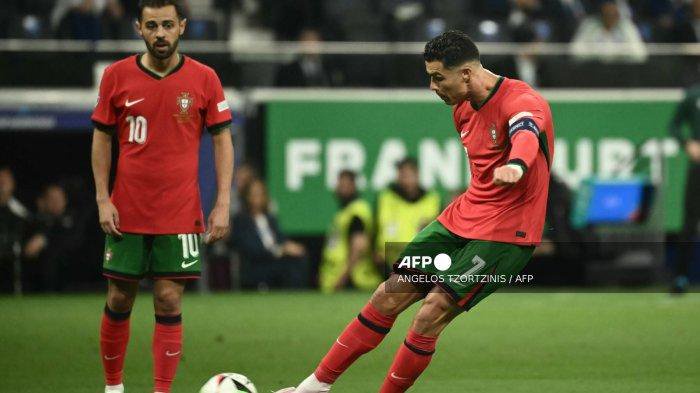 Pemain depan Portugal #07 Cristiano Ronaldo melakukan tendangan bebas saat rekan setimnya gelandang #10 Bernardo Silva menonton selama pertandingan sepak bola babak 16 besar UEFA Euro 2024 antara Portugal dan Slovenia di Frankfurt Arena di Frankfurt am Main pada tanggal 1 Juli 2024. Angelos Tzortzinis / AFP