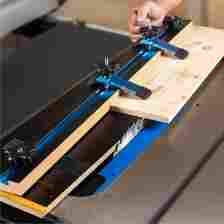 Tapering jig securing wooden board as it's pushed into table saw.