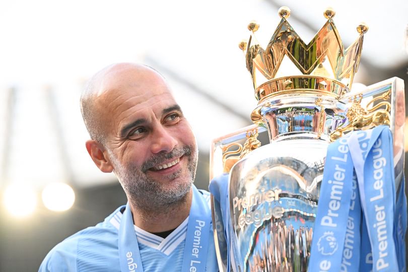 Pep Guardiola, Manager of Manchester City, poses for a photo with the Premier League title trophy following the team's victory in the Premier League match between Manchester City and West Ham United