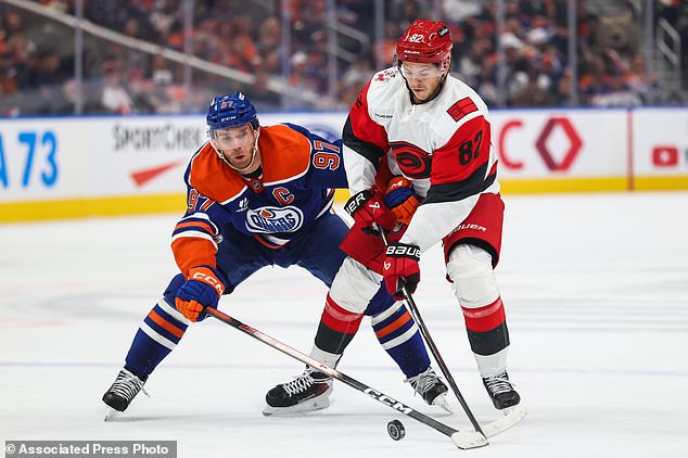 Edmonton Oilers' Connor McDavid (97) battles against Carolina Hurricanes' Jesperi Kotkaniemi (82) during the first period of an NHL hockey game in Edmonton, Alberta, Thursday, Oct. 22, 2026. (Codie McLachlan/The Canadian Press via AP)