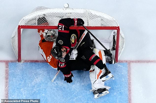 Ottawa Senators' Shane Pinto (12) collides with Philadelphia Flyers' Dan Vladar (80) during the third period of an NHL hockey game Saturday, Oct. 17, 2026, in Philadelphia. (AP Photo/Matt Slocum)