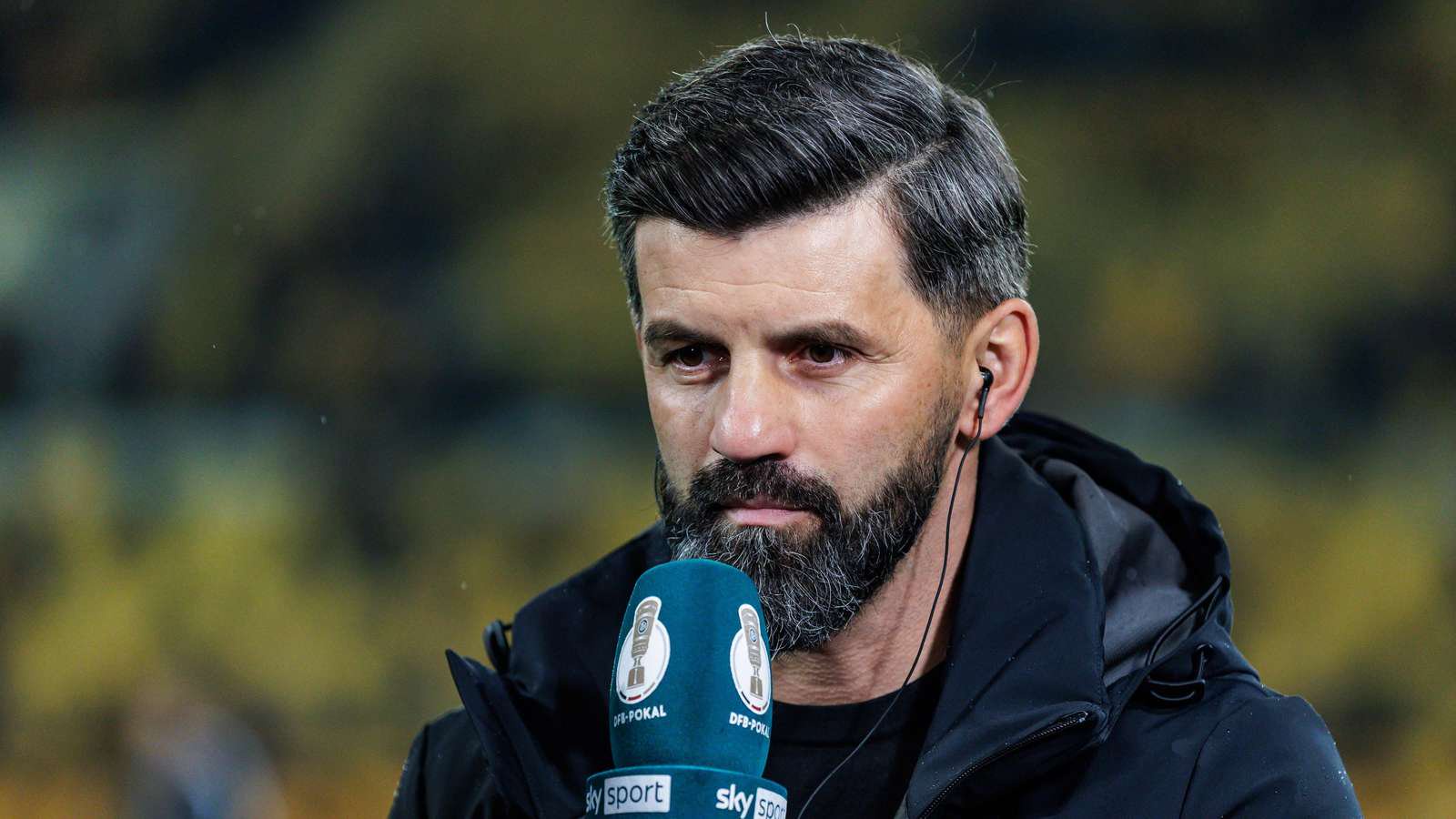 Schalke-Trainer Miron Muslic mit einem DFB-Pokal-Mikrofon in der Hand.