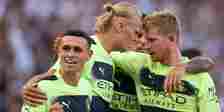 Manchester City players Erling Haaland, Kevin de Bruyne and Phil Foden celebrate a goal together.