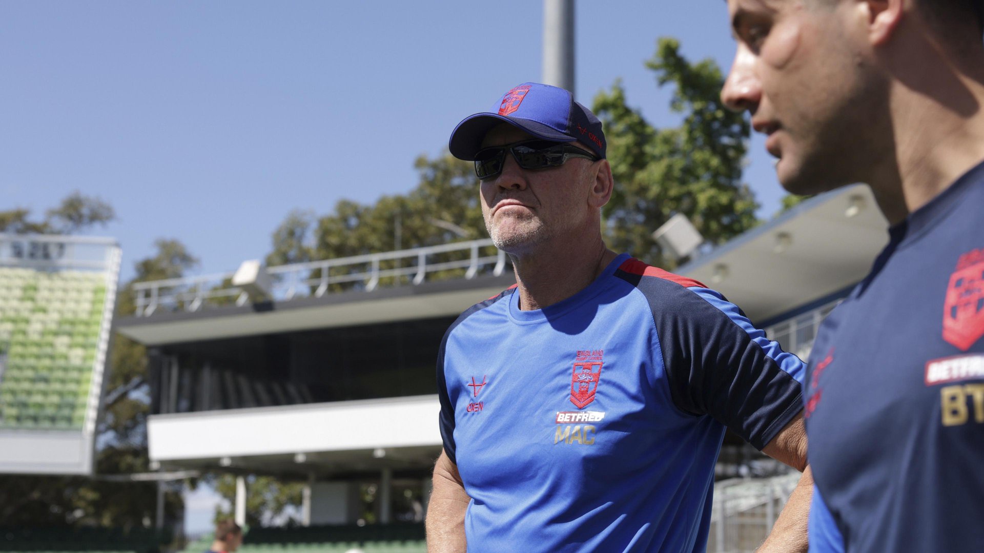 Brian McDermott, in a cap and sunglasses, looks into the distance