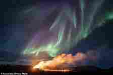 A view of the eruption area with the northern lights dancing in the sky near the town of Grindavik, Iceland, Tuesday April 16, 2024. The volcano in southwestern Iceland that erupted three times in December, January and February, sending lava towards a nearby community, keeps erupting. (AP Photo/Marco di Marco)