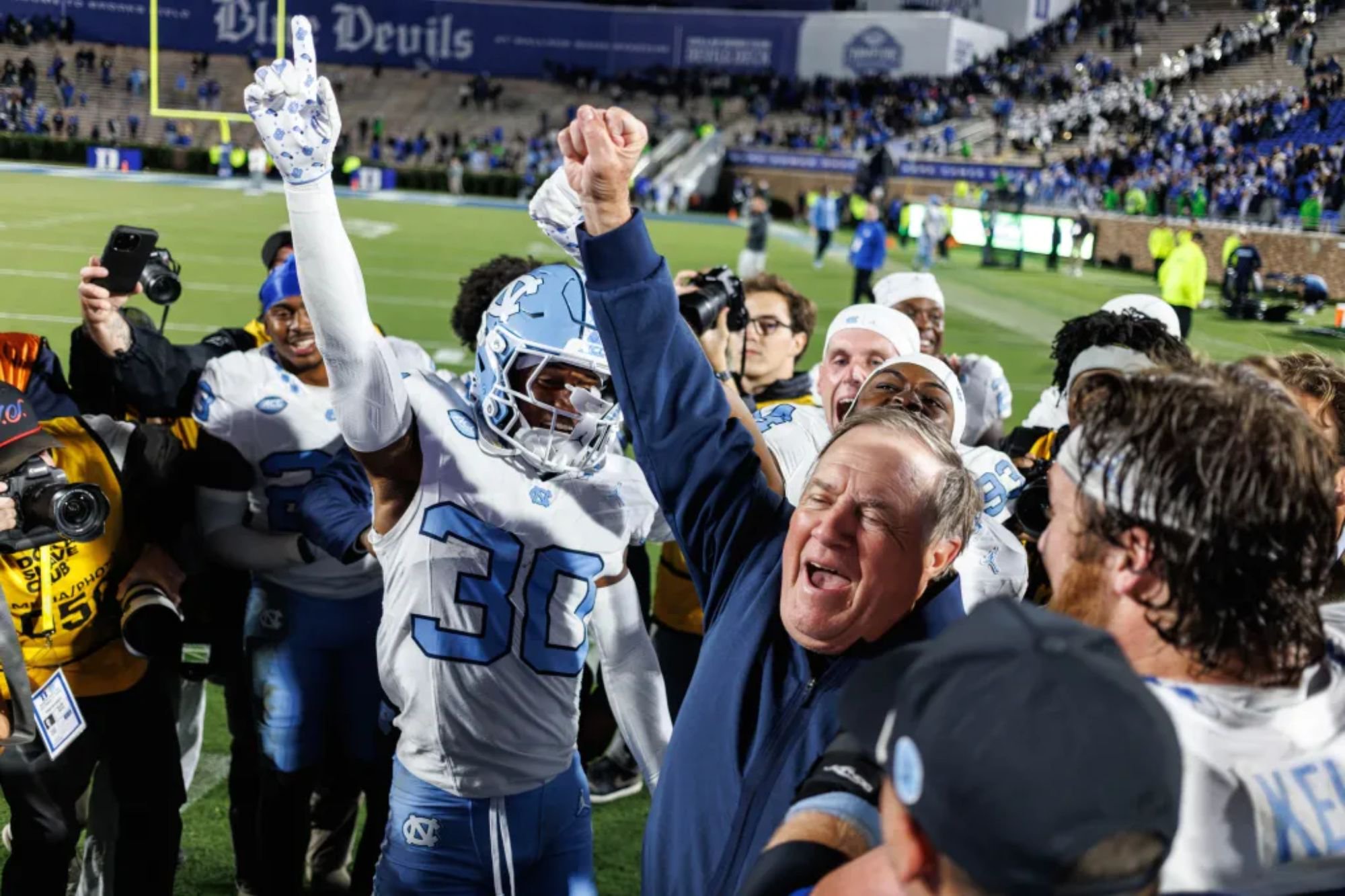 An image collage containing 1 images, Image 1 shows North Carolina head coach Bill Belichick celebrates with Jaziel Hart (30) after defeating Duke in a college football game