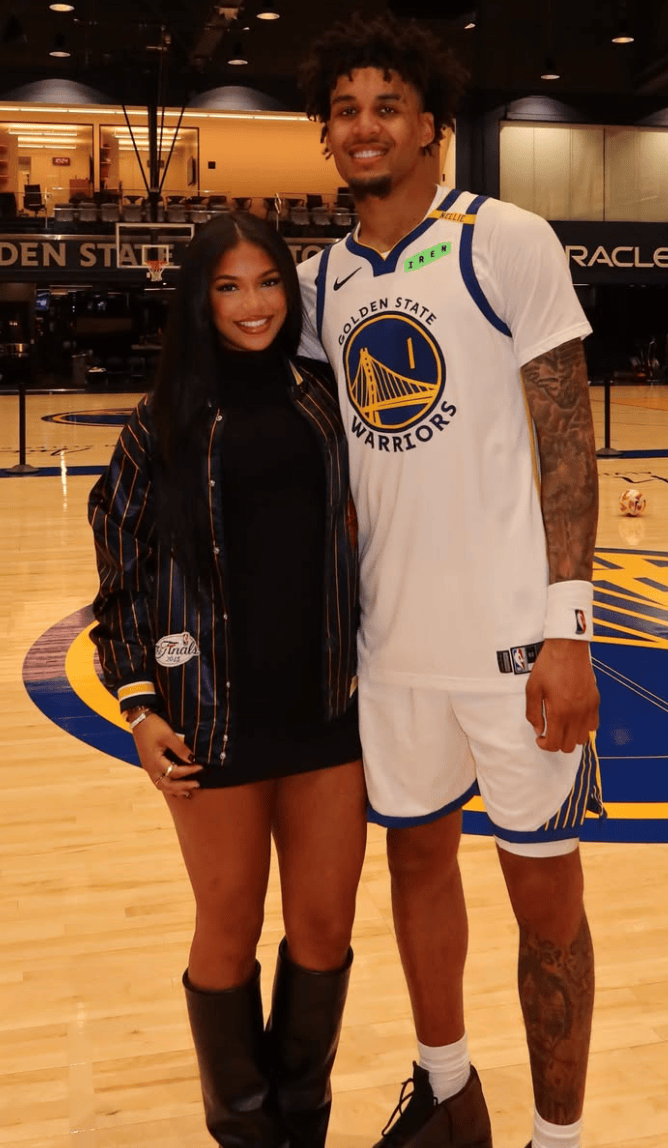 Brandin Podziemski standing on a basketball court with a woman.