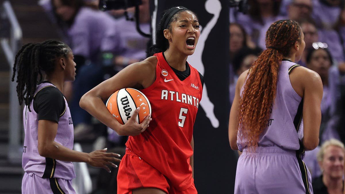 Angel Reese #5 reacts between Tiffany Hayes and Kiah Stokes during WNBA Finals game.