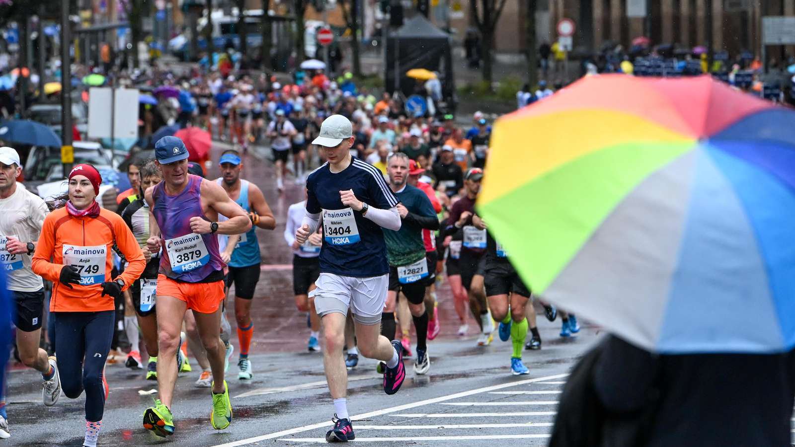 Frankfurt. 25.10.2026. Mainova Marathon, seit 1981 fuehrt die Laufveranstaltung die Sportler:innen durch die Stadt. Der erste Teil der Laufstrecke in stroemendem Regen. Zuschauer an der Strecke mit Schirmen und wetterfester Kleidung.TAGESHONORARVeroeffentlichung nur zur aktuellen Berichterstattung, unter Beachtung des Medienprivilegs.Vereinbarung ueber Abtretung von Persoenlichkeitsrechten der abgebildeten Person(en), Model / Product Release liegt nicht vor. Foto: Renate Hoyer,  60316 Frankfurt.