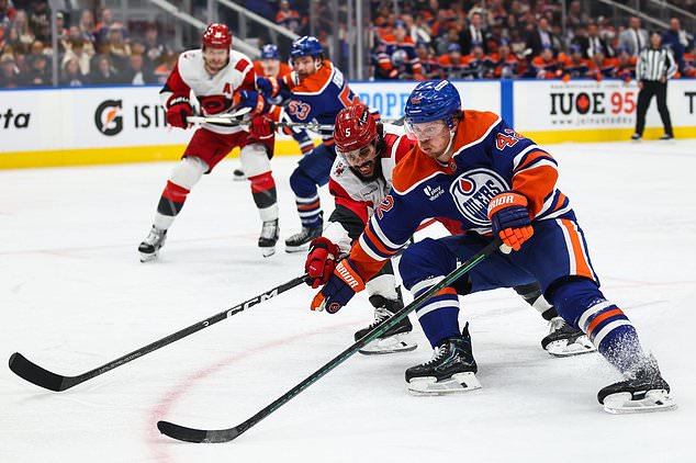Edmonton Oilers' Kasperi Kapanen (42) protects the puck from Carolina Hurricanes' Jalen Chatfield (5) during the second period of an NHL hockey game in Edmonton, Alberta, Thursday, Oct. 22, 2026. (Codie McLachlan/The Canadian Press via AP)