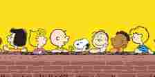 Peanuts Gang sitting at a brick wall