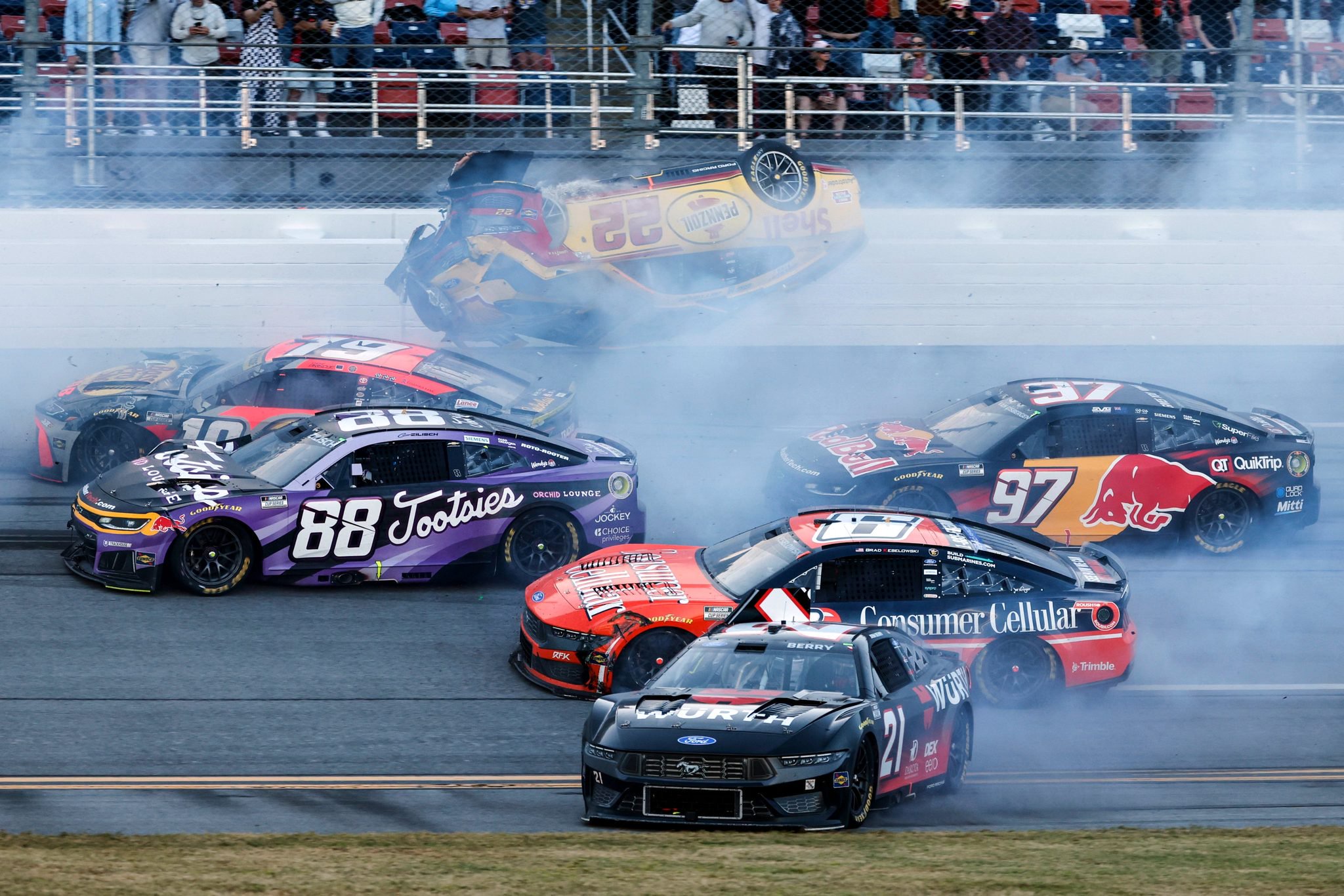 NASCAR crash at Talladega: car #22 flipped upside down in a smoky pileup, with #88, #97, #21 and others nearby.