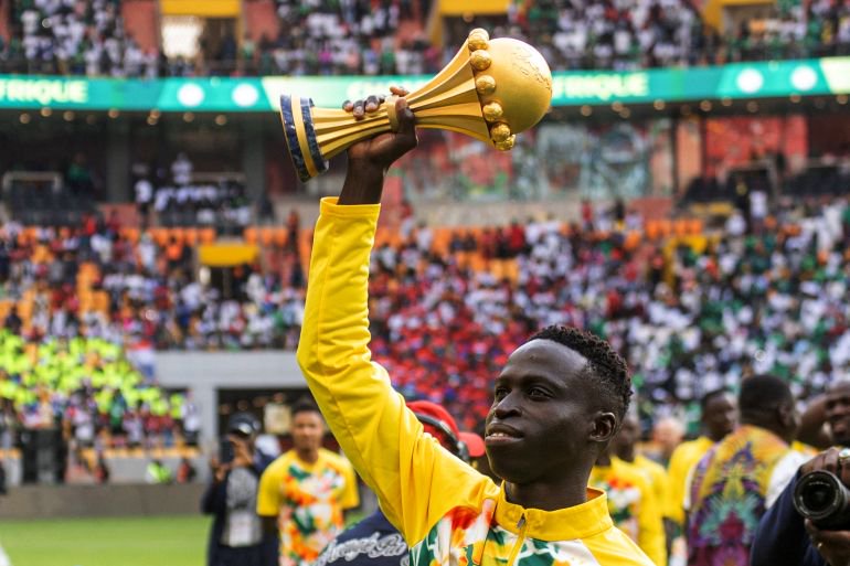Senegal's Krepin Diatta celebrates as he holds the AFCON trophy.