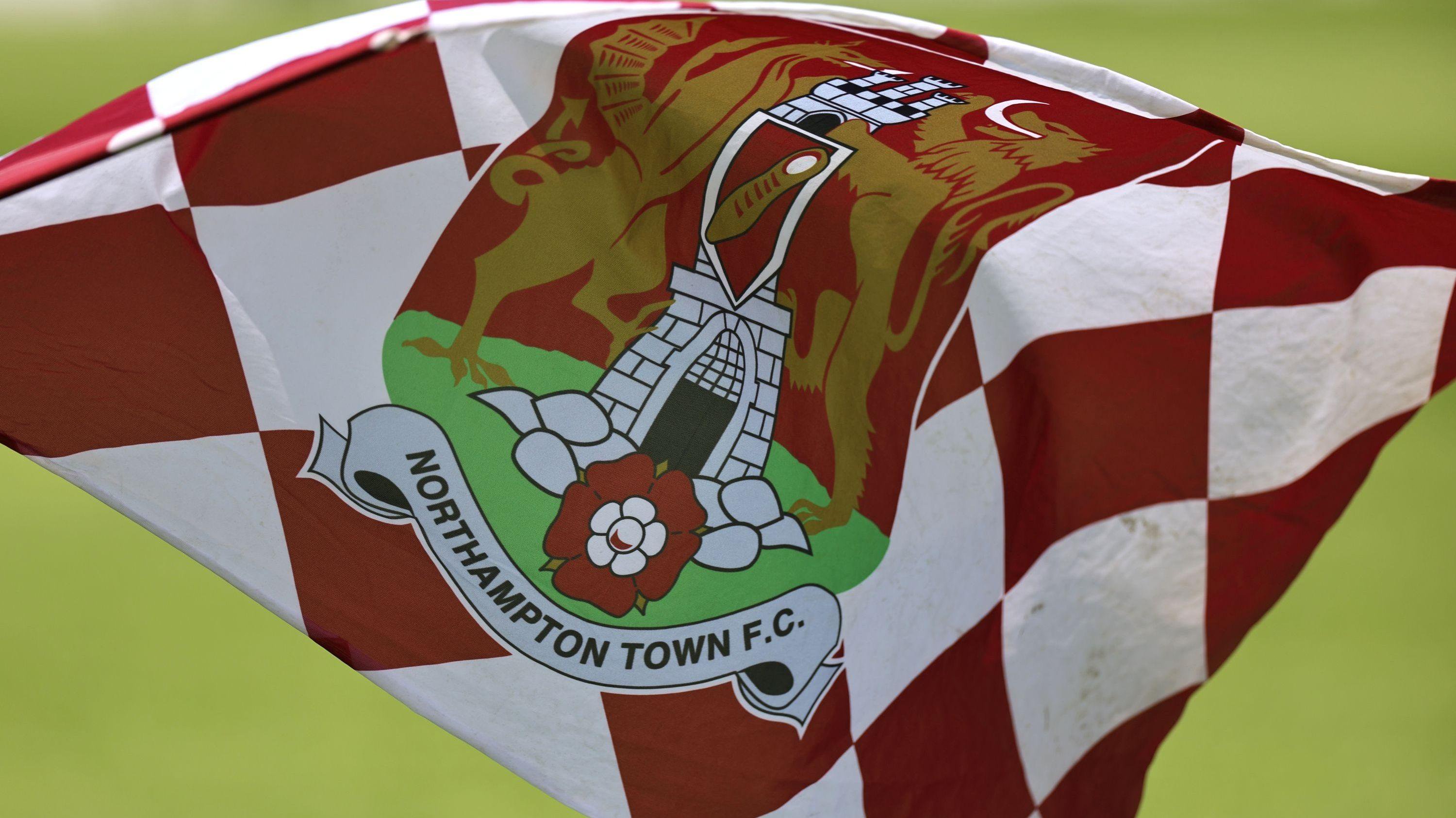 A white and claret chequered Northampton Town flag fluttering against a green backdrop.