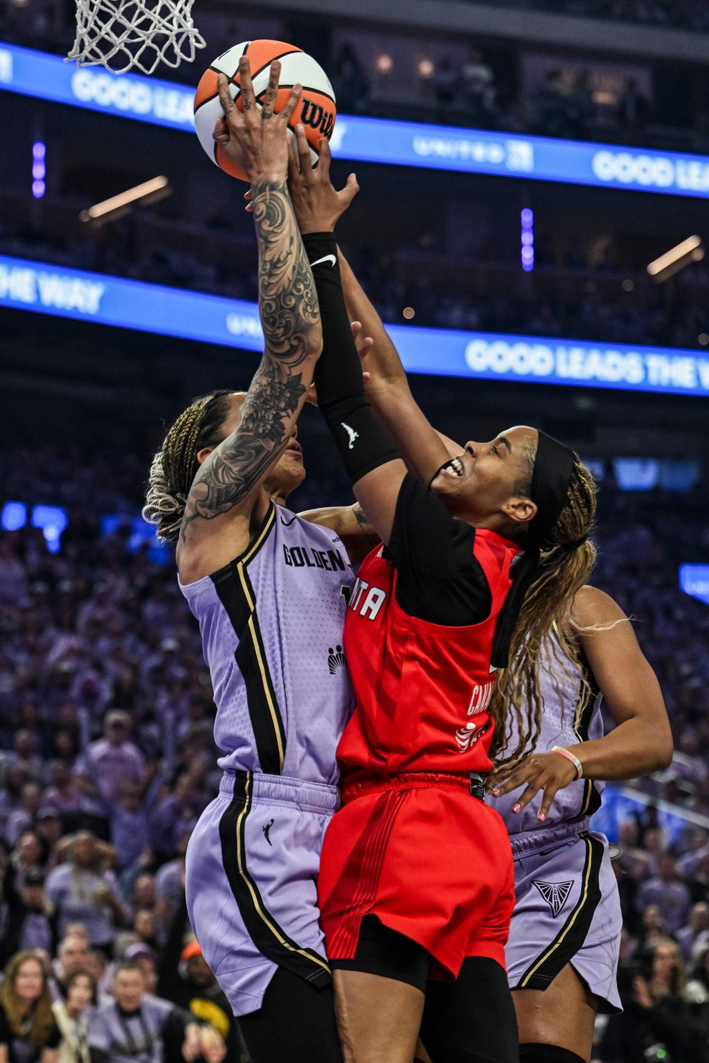Gabby Williams and Jordin Canada battle for a rebound during a basketball game.