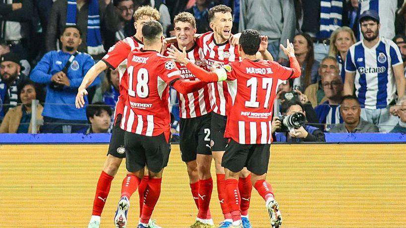 PSV Eindhoven players in a huddle, in red and white striped football shirts, as they celebrate a goal