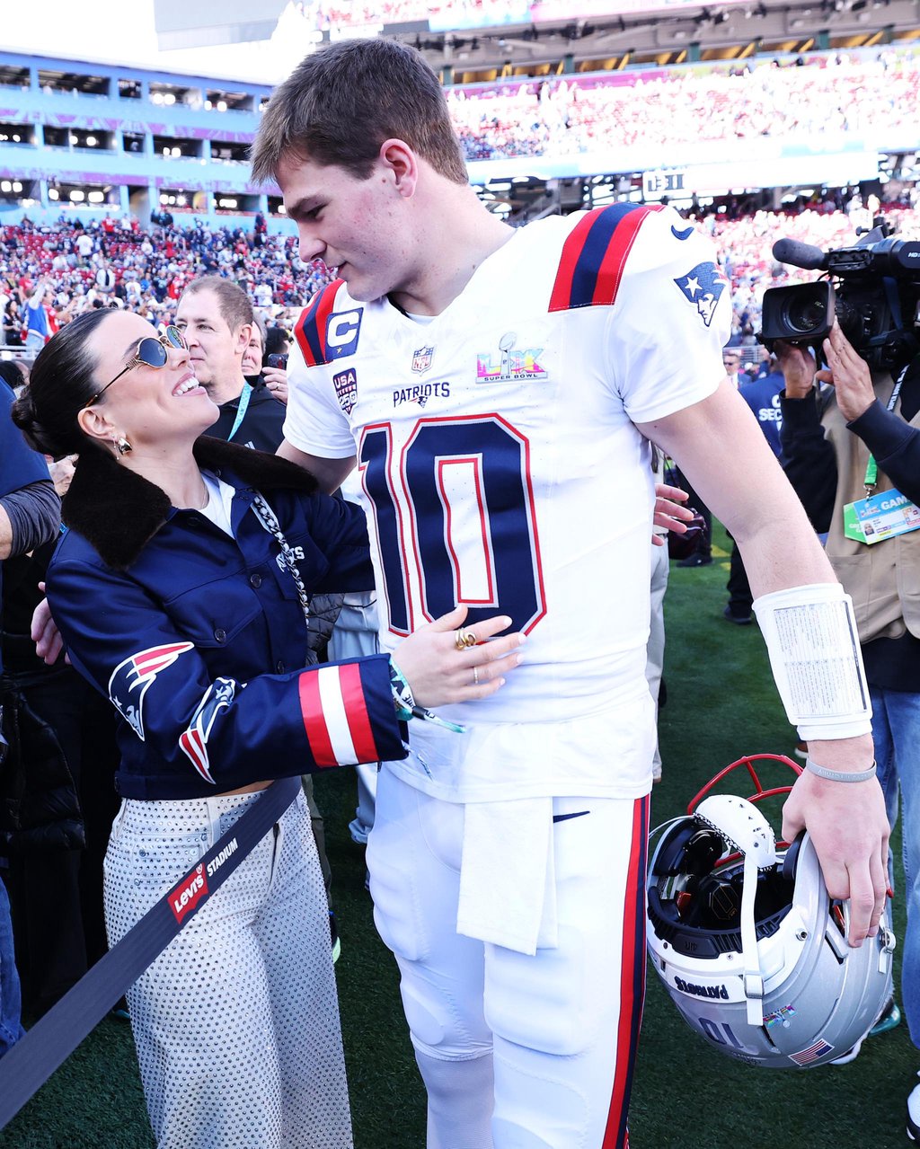 Drake Maye hugs his wife Ann Michael Maye on the field before the start of a game.
