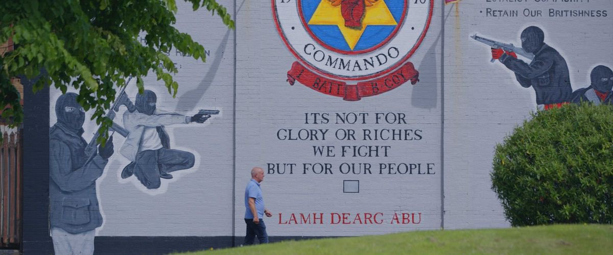 Former Star of the Sea player Raymond McCord walks past a loyalist mural the Rathcoole Estate in North Belfast where he grew up