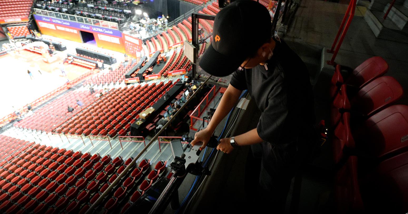 A person adjusts camera equipment overlooking an arena.