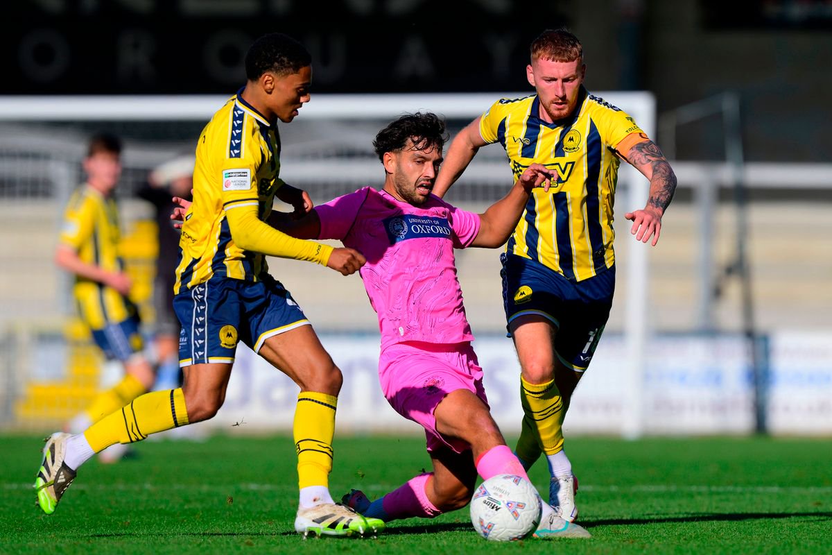 Zac McEachran of Oxford City challenges for the ball with Caleb Roberts of Torquay United and Matt Worthington of Torquay United during the Emirates FA Cup Fourth Round Qualifying match between Torquay United and Oxford City at Plainmoor, Torquay on Saturday 17th October 2026 - PHOTO: Frankie OKeeffe/PPAUK