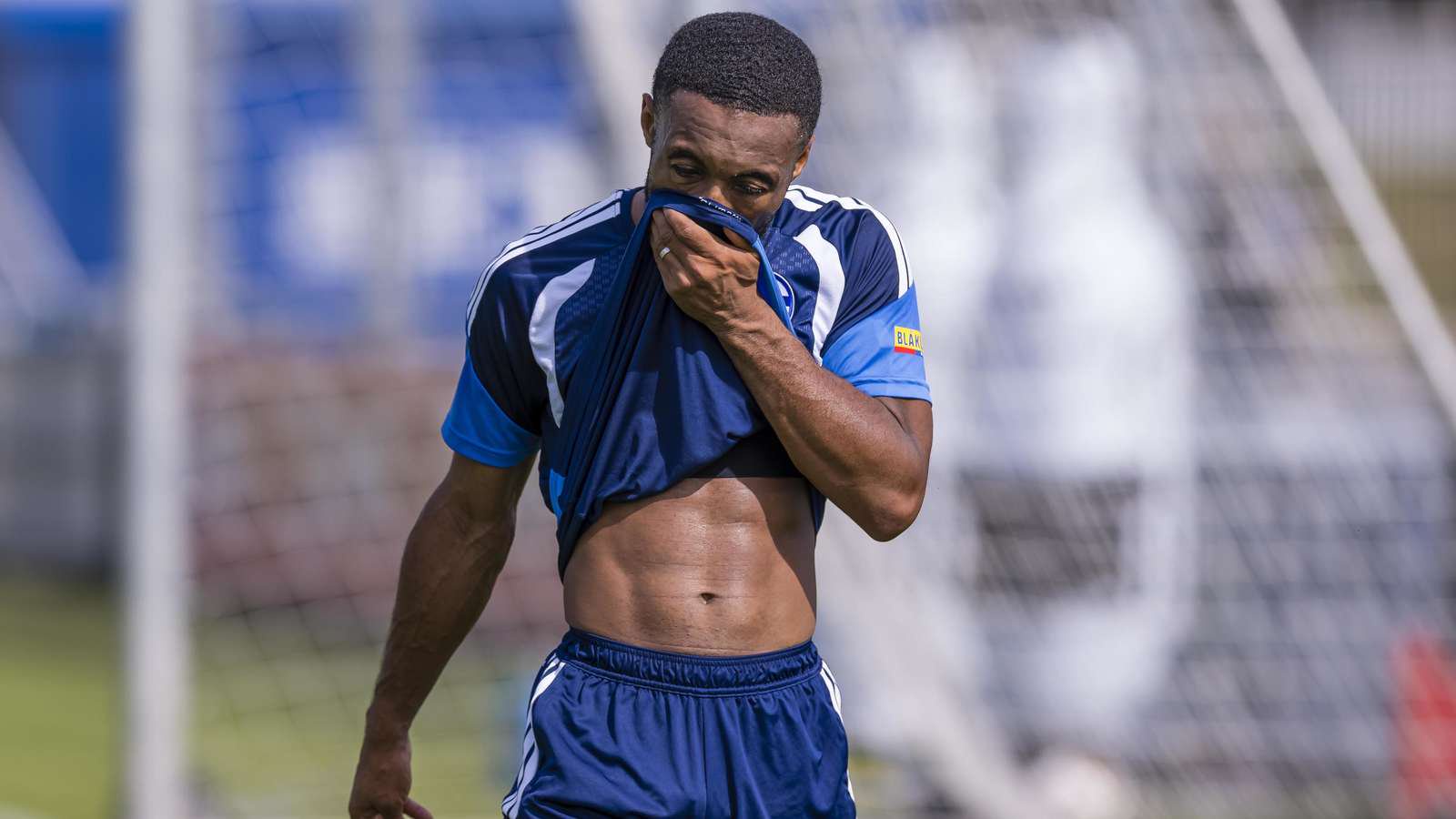 Moussa Sylla zieht das Trikot im Schalke-Training über das Gesicht.