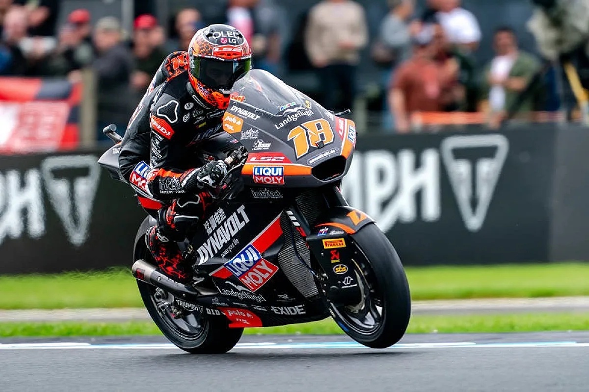 Rider in black and orange leathers on a Moto2 bike with number 78 at a Moto2 race track, leaning into a corner