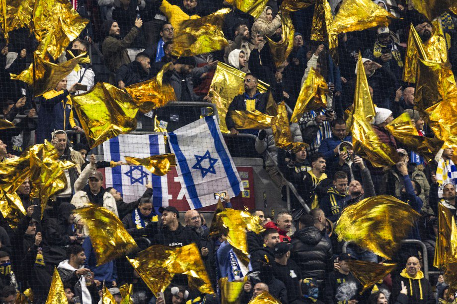 Maccabi supporters wave yellow flags next to Israeli flags during the UEFA Europa League, League phase - Matchday 4, football match between Ajax Amsterdam and Maccabi Tel Aviv at the Johan-Cruijff stadium, in Amsterdam on November 7, 2024. [Robin van Lonkhuijsen /AFP via Getty Images]