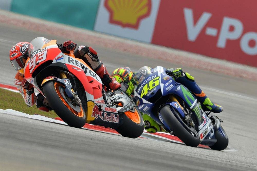Marc Marquez on Repsol Honda leads Valentino Rossi on Movistar Yamaha through a MotoGP corner, with Shell and V-Power signage behind.