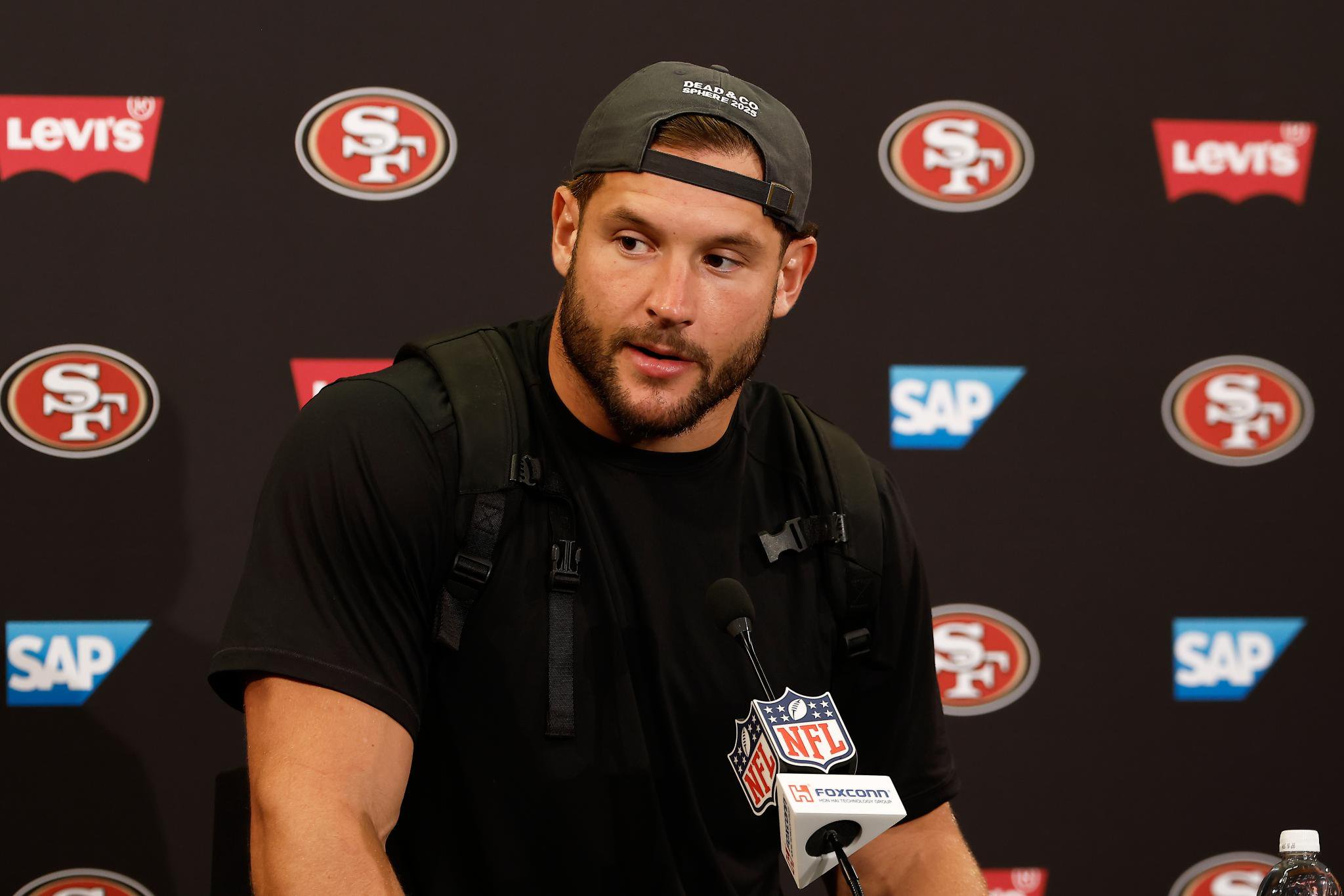San Francisco 49ers defensive end Nick Bosa speaks at a news conference in front of a sponsor backdrop.