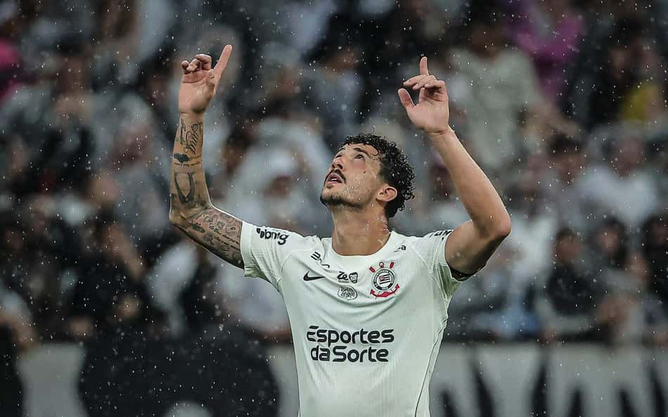 Gustavo Henrique celebra em campo sob chuva, braços erguidos, camisa branca.