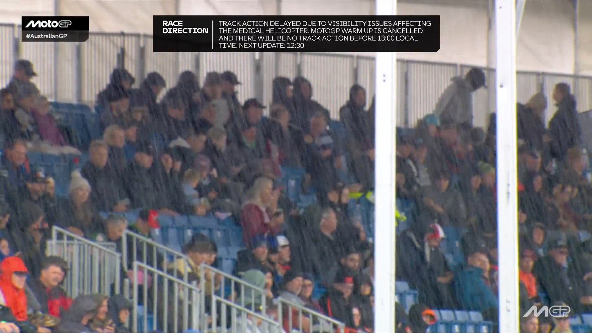 Spectators sit in rain-soaked grandstands at Phillip Island as MotoGP track action is delayed by poor visibility