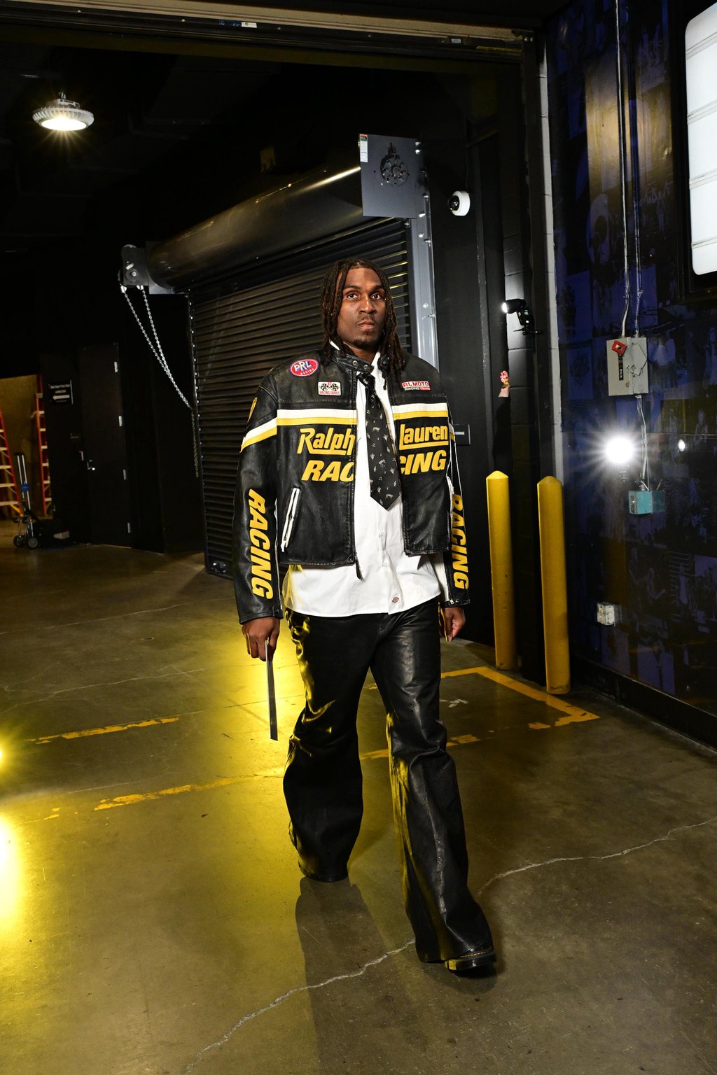 Kevon Looney arriving at the arena wearing a black Ralph Lauren Racing leather jacket and matching pants.