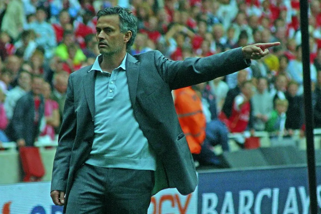 José Mourinho gesturing while standing on the sideline of a football match.