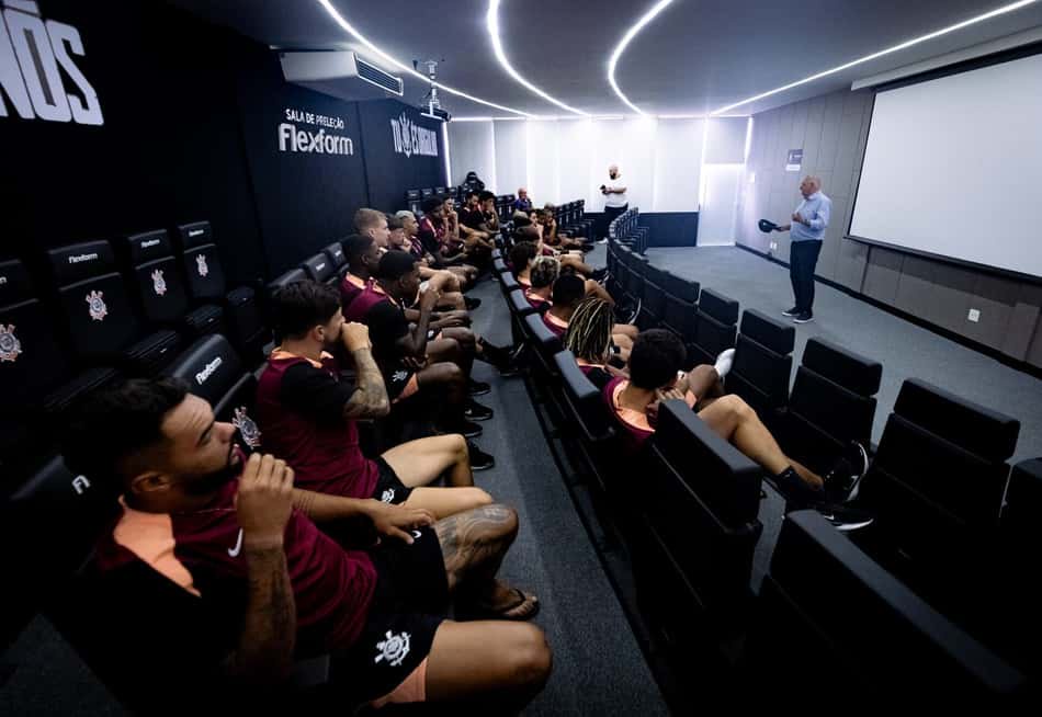 Osmar Stabile apresenta elenco de futebol em palestra, com jogadores sentados em sala de pré-temporada.