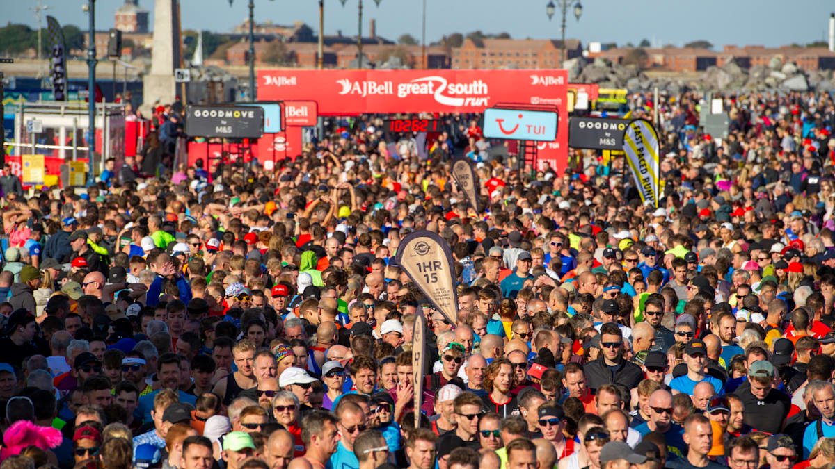 A thick crowd of runners with the red Great South Run starting line behind