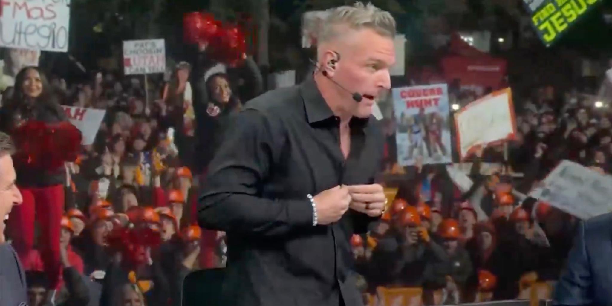 Pat McAfee unbuttons his black shirt on College GameDay in front of a crowd of fans.