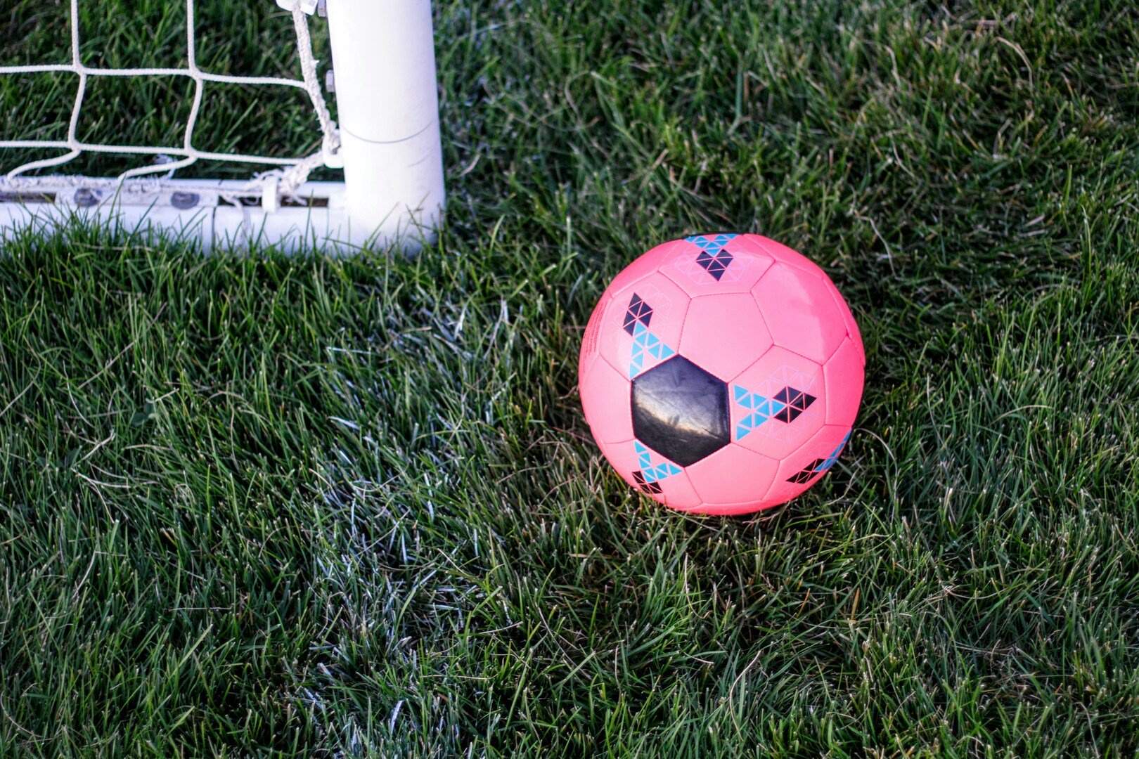 Pinker Fußball neben Torstange