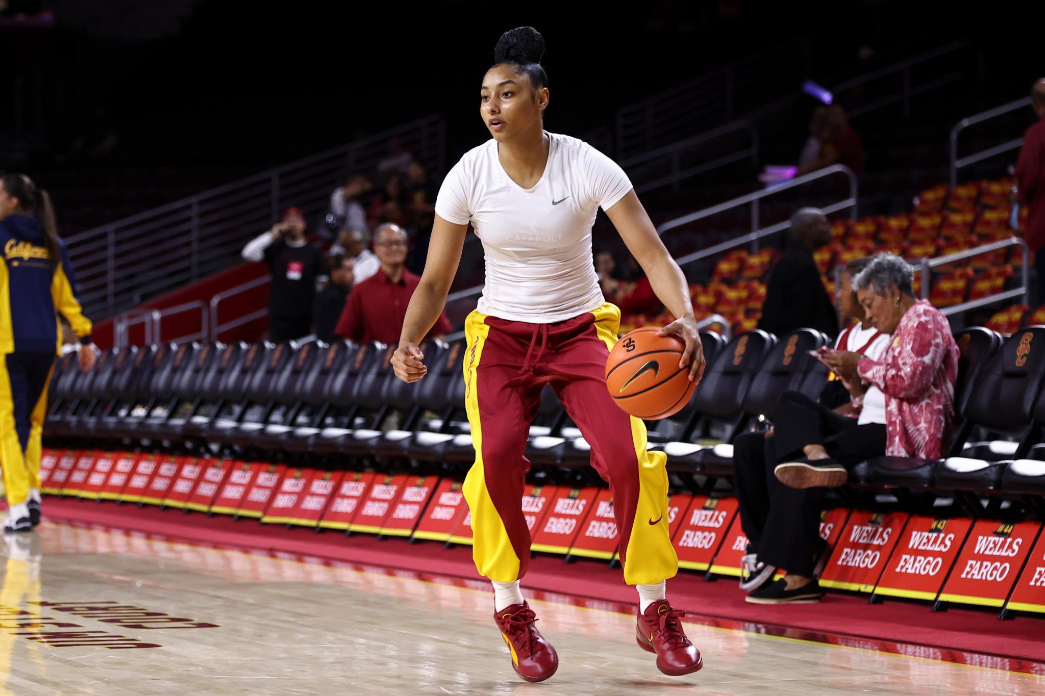 A female basketball player dribbling the ball on a court during a game against California.