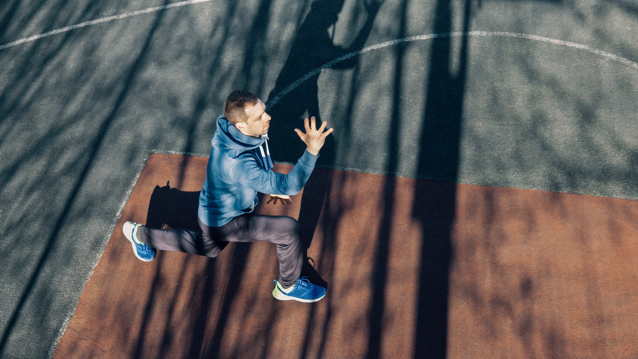 Ein Mann Outdoor in Sportkleidung macht einen Lunge.