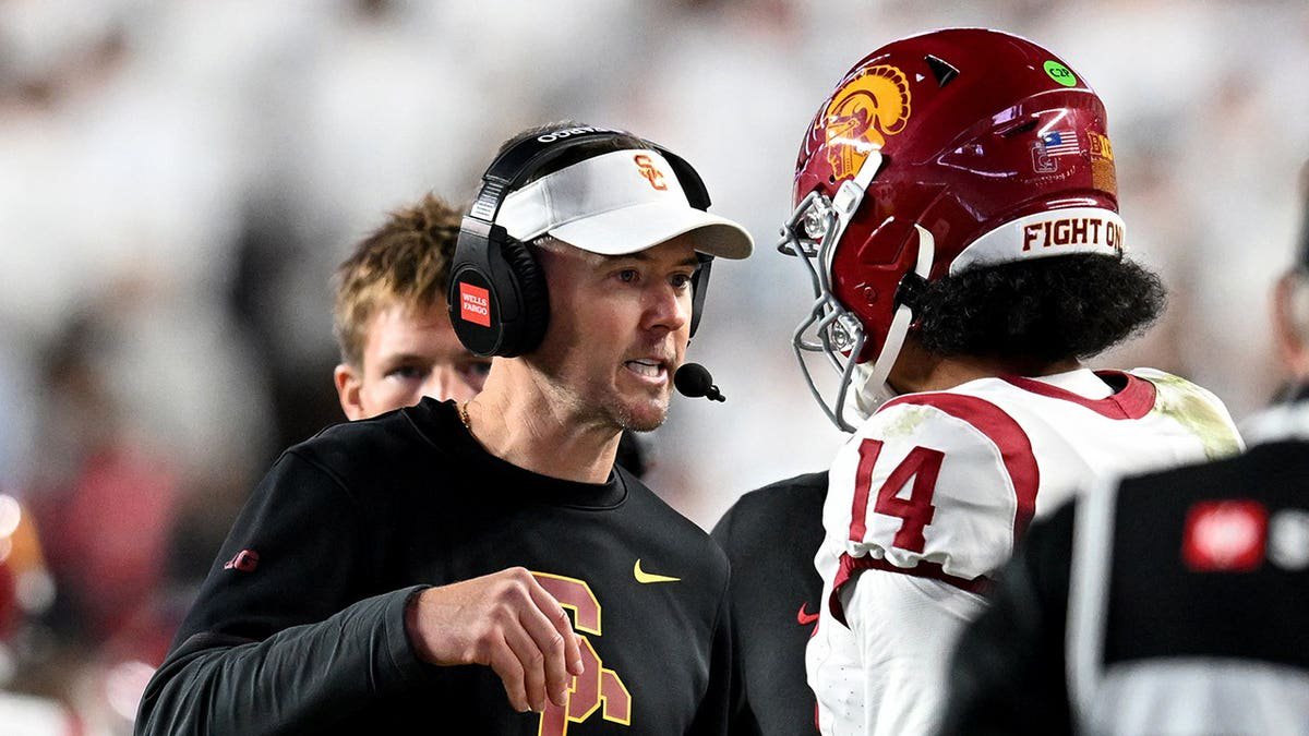 Lincoln Riley talks with quarterback Jayden Maiava between plays during a college football game.