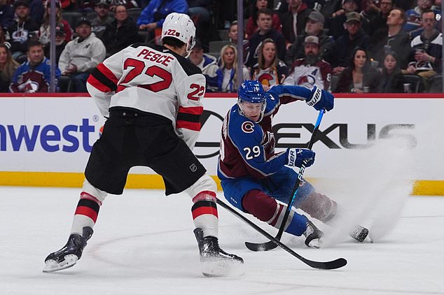 Colorado Avalanche center Nathan MacKinnon, right, looks to pass the puck as New Jersey Devils defenseman Brett Pesce covers in the first period of an NHL hockey game Wednesday, Oct. 28, 2026, in Denver. (AP Photo/David Zalubowski)