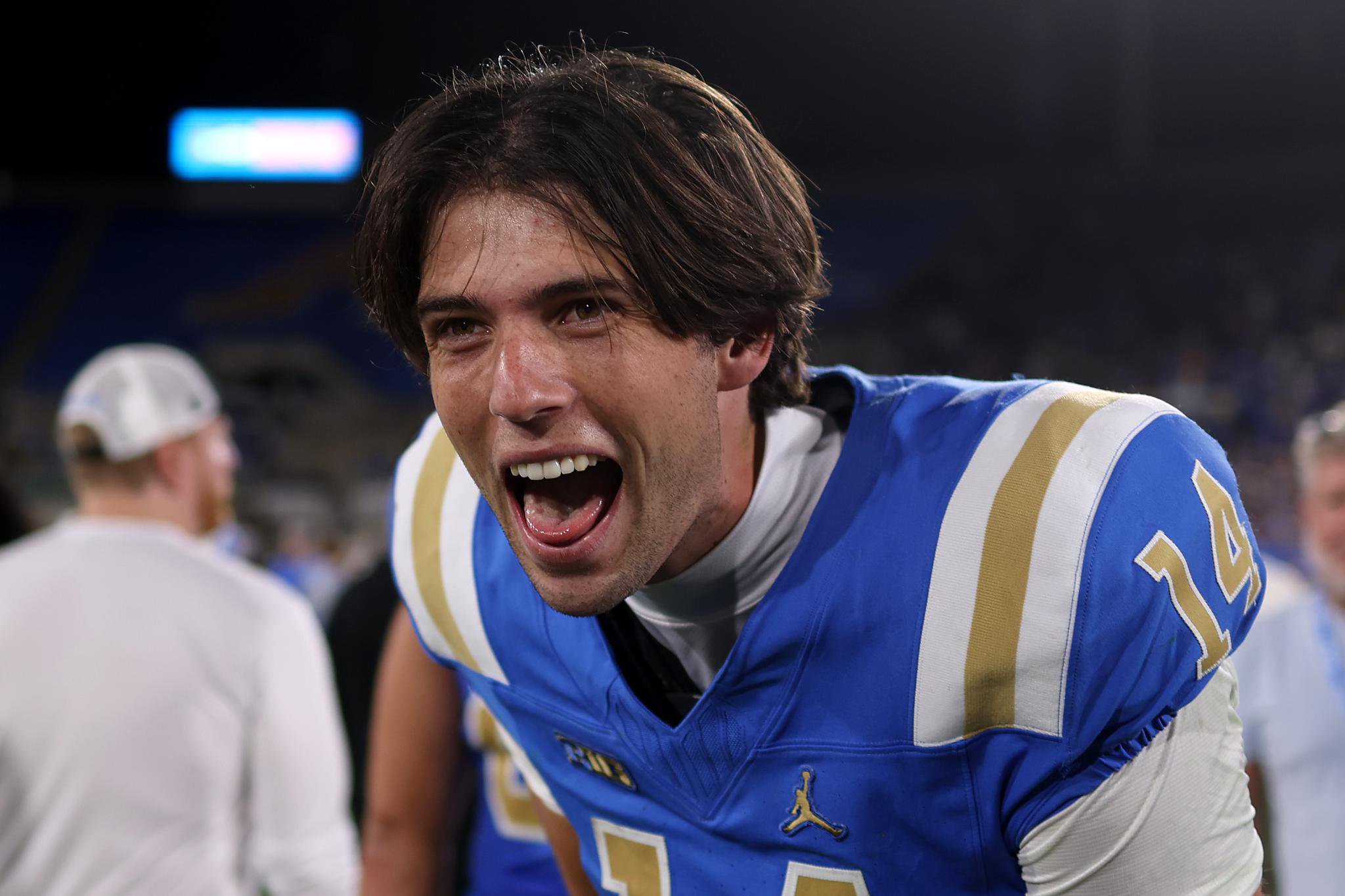 A UCLA football player yells in celebration.