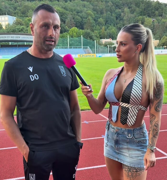 Coach speaking to female reporter with pink microphone on running track