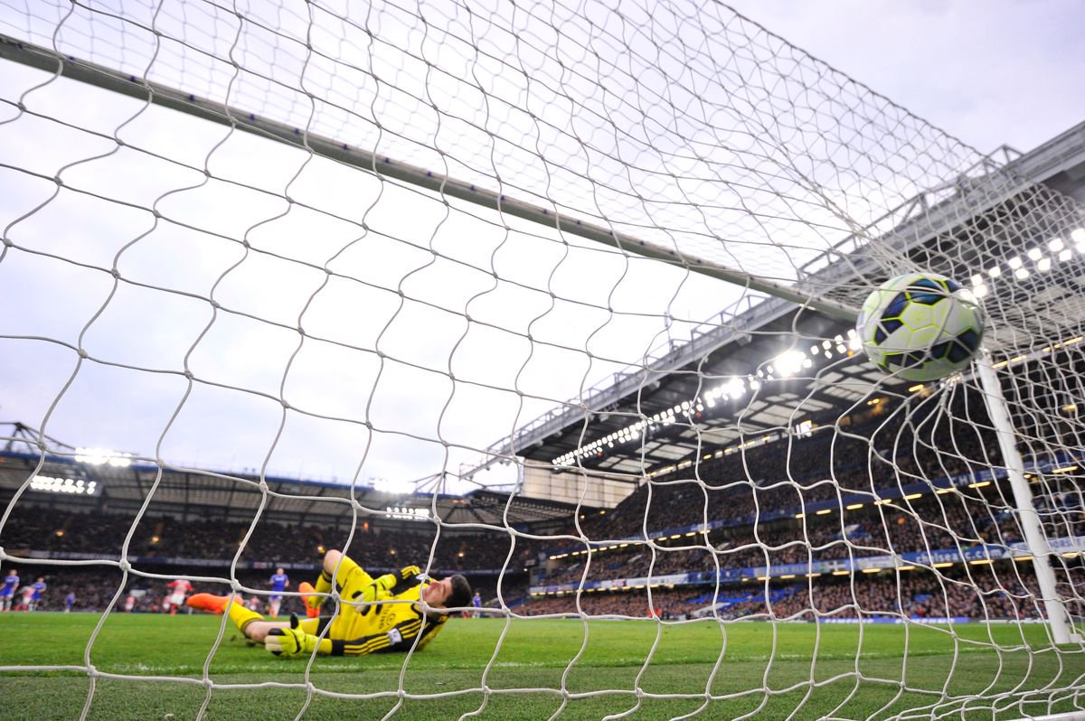 The ball slams into the back of the net as Chelsea's Belgian goalkeeper Thibaut Courtois (C) falls into his own goal after chasing back but failing to keep out a long range shot from Stoke City's Scottish midfielder Charlie Adam (unseen) who scored to equalise 1-1 during the English Premier League football match between Chelsea and Stoke City